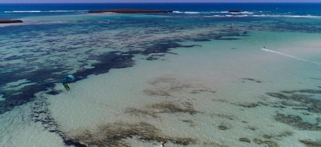 Rider en famille avec matériel de kitesurf sur la plage du Sakalava Lodge